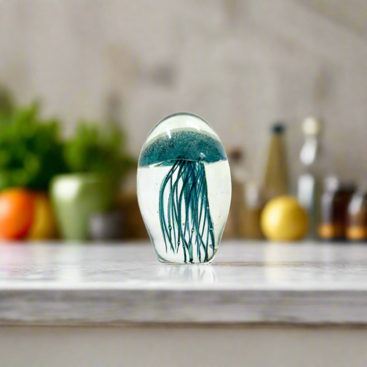 Mejello 9.8cm: A Glowing Masterpiece of Glass Art
Elevate your home decor with the Mejello 9.8cm, a breathtaking handmade clear orb featuring a mesmerizing teal jellyfish shape. Suspended within the glass are delicate silver bubbles and tentacles, adding an extra layer of depth and visual interest.