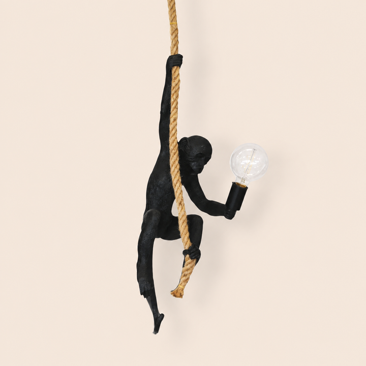 Black resin monkey on rope hanging lamp on warm beige background