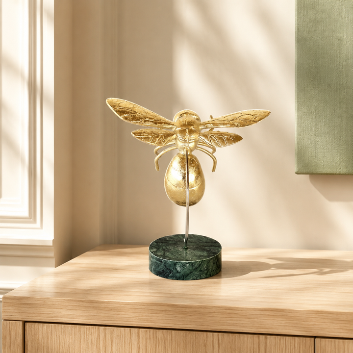 Gold bumblebee on marble base styled in a warm interior