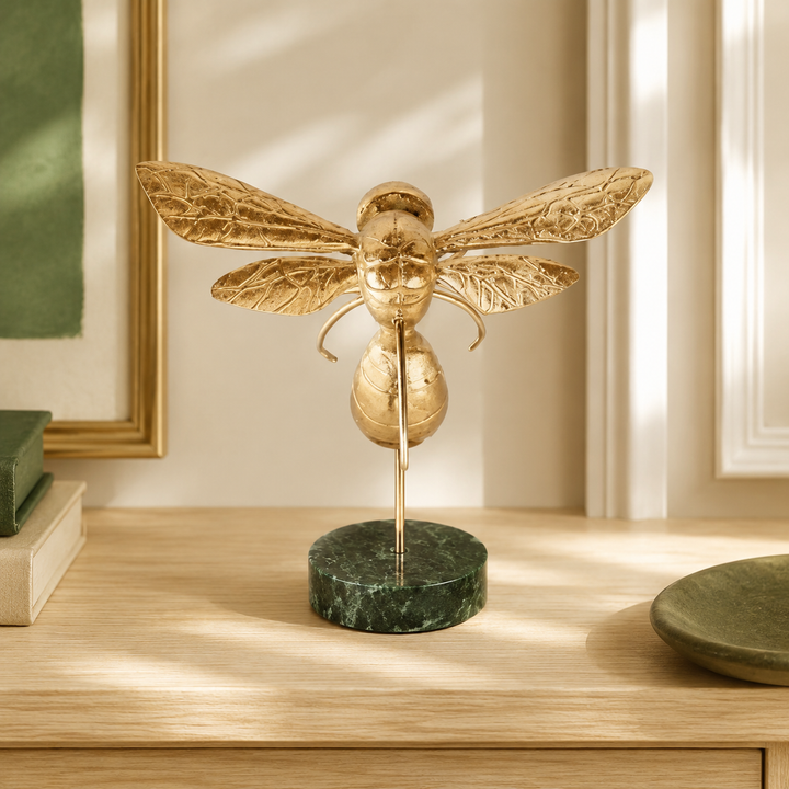 Medium gold bumblebee on marble base styled in a warm interior