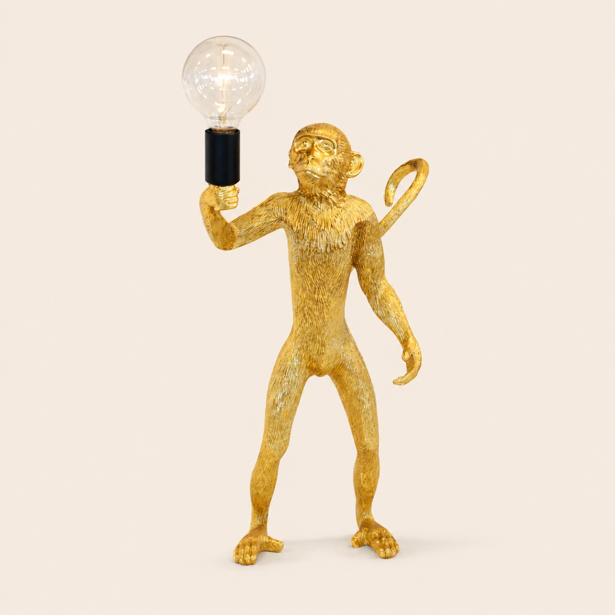 Standing gold resin monkey lamp on warm beige background