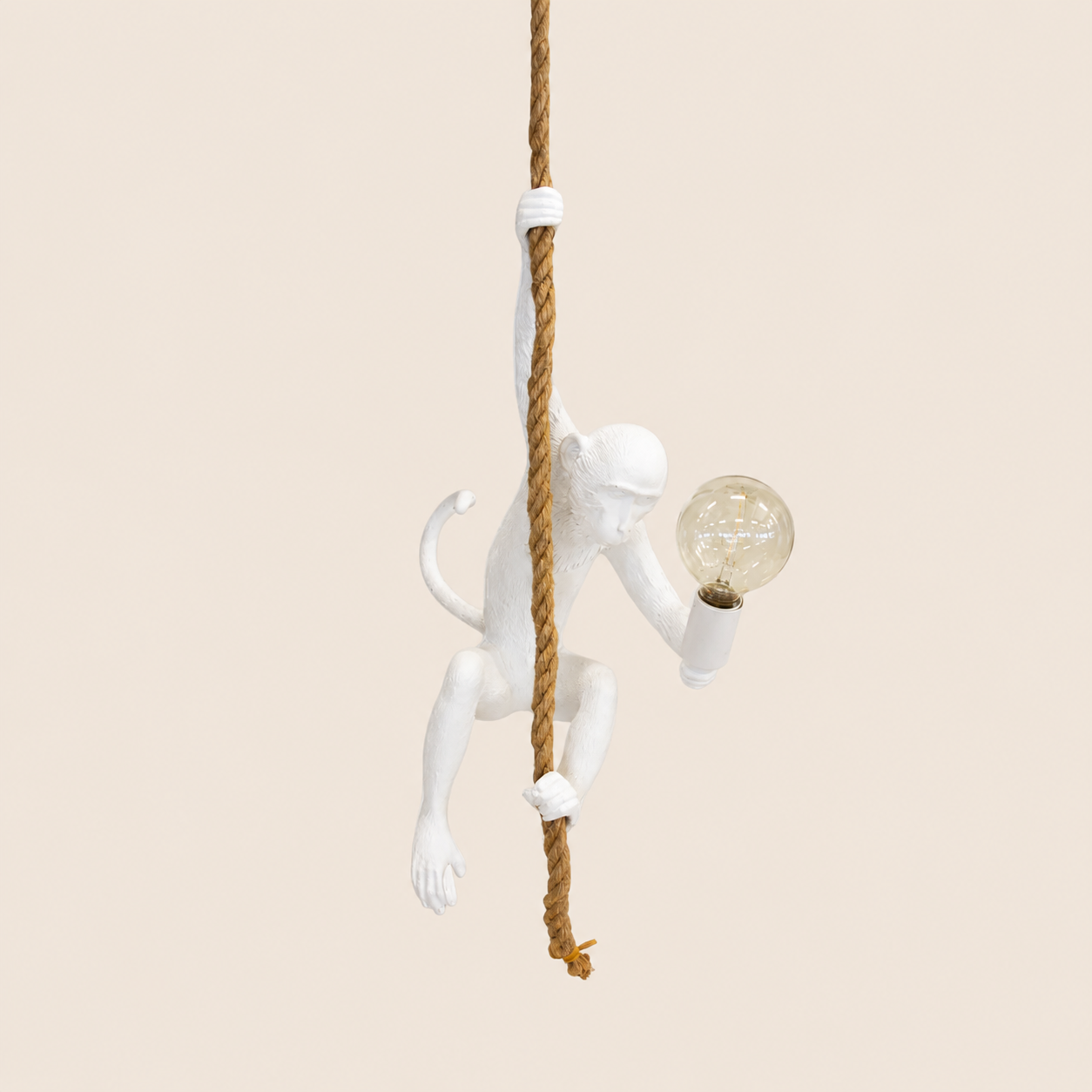 White resin monkey on rope hanging lamp on warm beige background